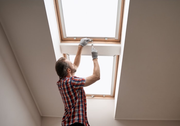 Homme installant une lucarne au plafond.