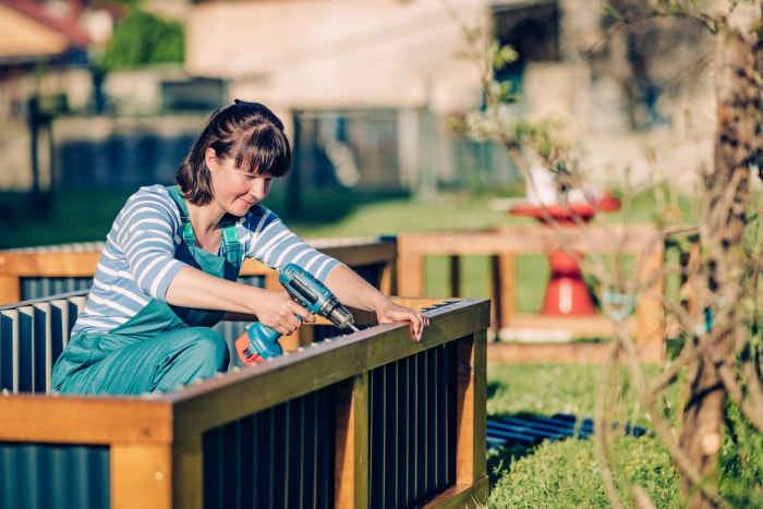 iStock-1318366155 14 astuces pour protéger votre jardin des intempéries Une femme construit un lit de plantation surélevé