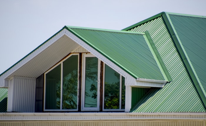 vue du dernier étage d'une grande maison avec un toit en métal vert avec des fenêtres donnant sur le grenier