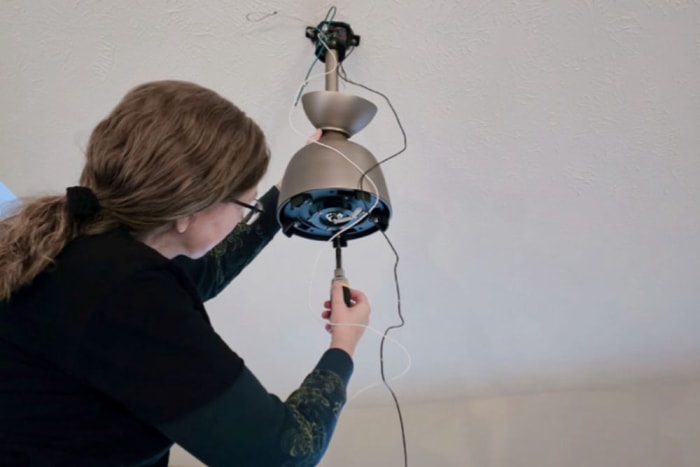 Une personne installe la base du ventilateur de plafond Barn by Minka-Aire dans son plafond.