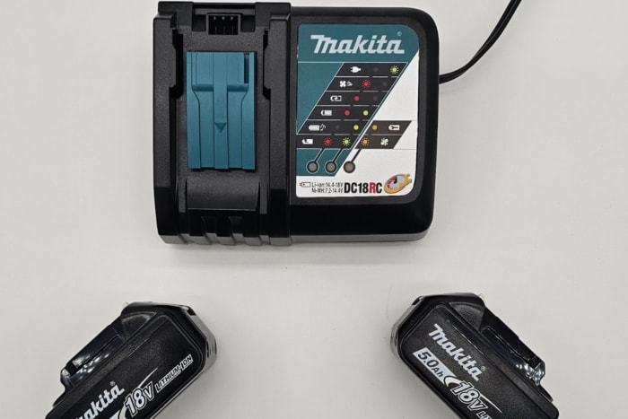 Les batteries de la perceuse à angle droit Makita disposées à côté de leur chargeur