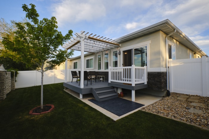 Maison en tôle avec petite pergola et terrasse.