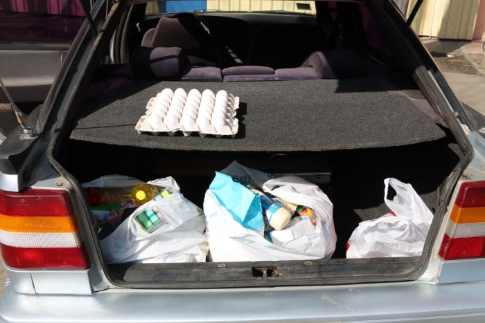 Sacs à provisions en plastique contenant de la nourriture dans le coffre d'une voiture. COVID-19.