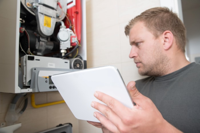 Un homme utilise une tablette numérique pour réparer un four.