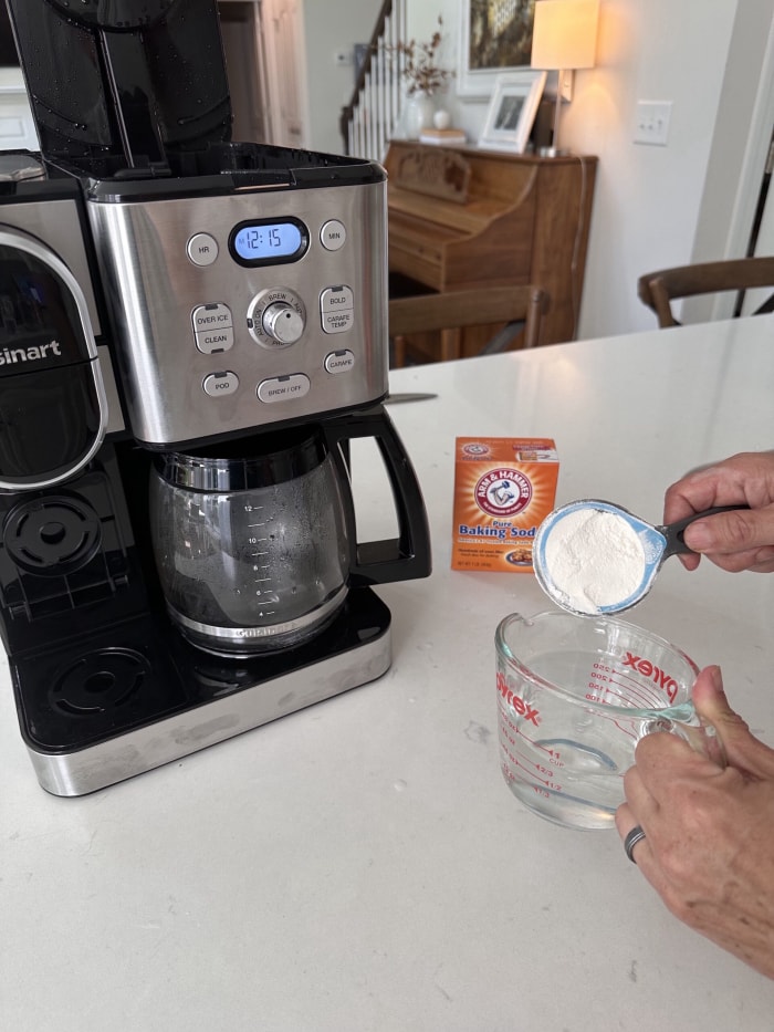 déposer une cuillère de bicarbonate de soude dans une tasse à mesurer avec une cafetière sur le comptoir de la cuisine