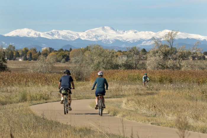 En parcourant le sentier pavé autour du lac avec le mont Evans enneigé en arrière-plan, les visiteurs aiment faire du vélo dans le parc d'État Cheery Creek du Colorado à Denver.