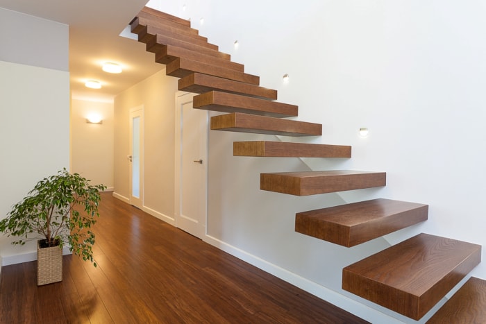 Un escalier flottant en noyer dans un couloir moderne.