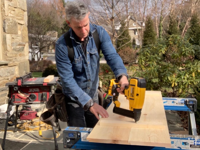 Une personne utilisant l'agrafeuse DeWalt Crown pour fixer un morceau de bois lors d'un test pratique.