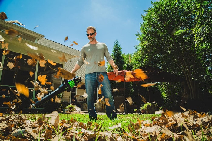 Une personne utilisant le meilleur souffleur sans fil pour enlever les feuilles d'un jardin