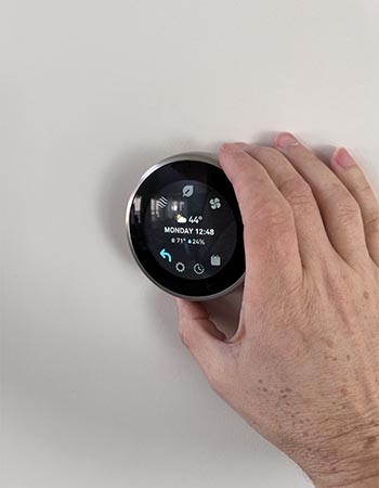 Une personne utilisant le cadran du thermostat Google Nest Learning pour régler manuellement ses paramètres pendant les tests.