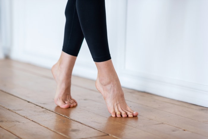 Une personne pieds nus marchant sur la pointe des pieds sur des planchers en bois.