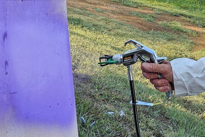 Une personne utilisant le pulvérisateur Wagner Paint pour peindre un objet blanc en violet.