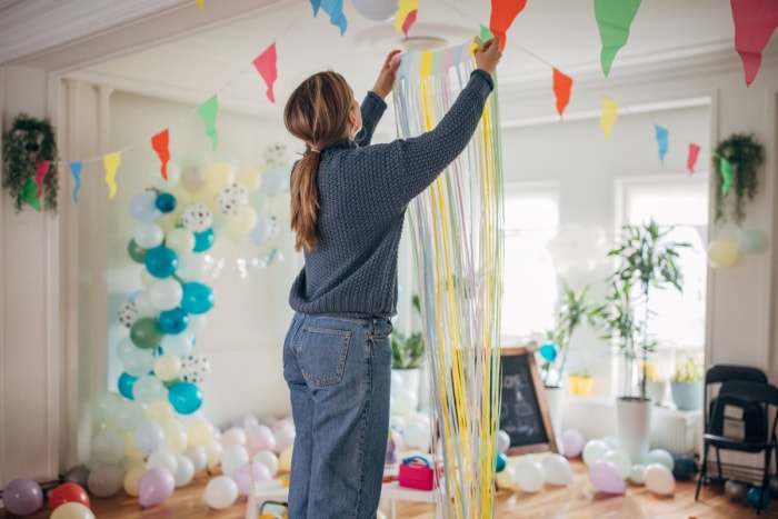 Femme accrochant un rideau de papier dans une pièce avec des ballons.