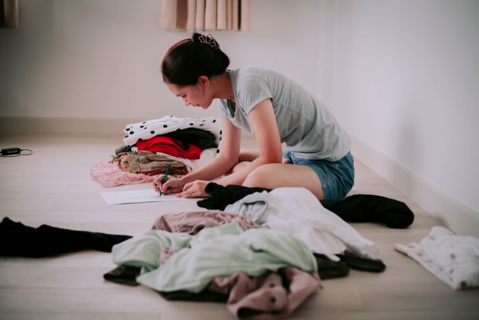 Une femme apporte ses vêtements à vendre et calcule l'argent qu'elle recevra de la vente.