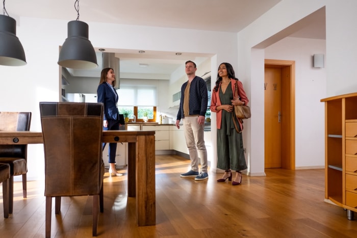 Un agent immobilier montre à un jeune couple une maison ouverte dans la salle à manger.