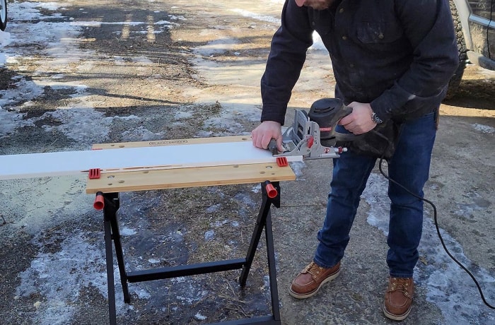 Une personne utilise une scie pour découper une planche posée sur le meilleur établi portable.