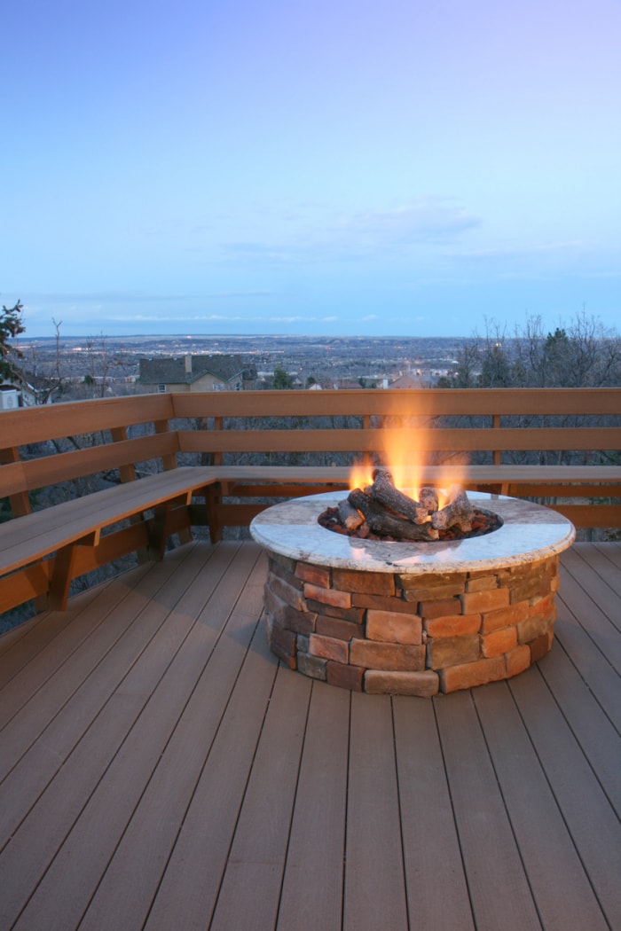 Terrasse et foyer avec vue sur les lumières de la ville au crépuscule. Focus sur le foyer