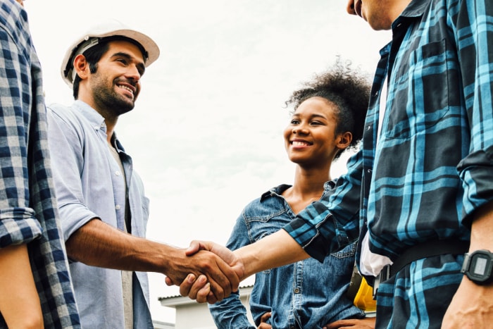 Des entrepreneurs multiraciaux se serrent la main et sourient.