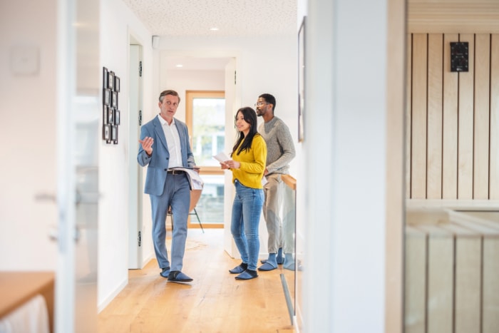 Agent immobilier masculin montrant à un jeune couple l'intérieur d'une maison