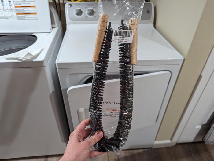 Une personne tenant la brosse à charpie flexible Holikme 2-Pack Dryer Vent Cleaner avant le test.