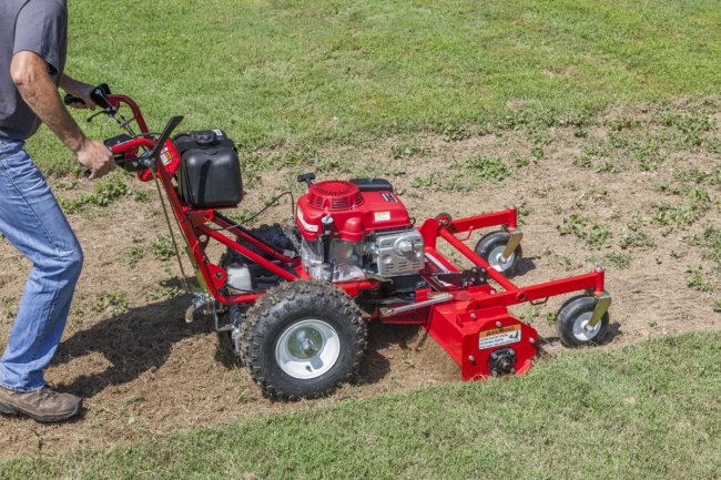 Personne utilisant une machine à ratisser de couleur rouge.