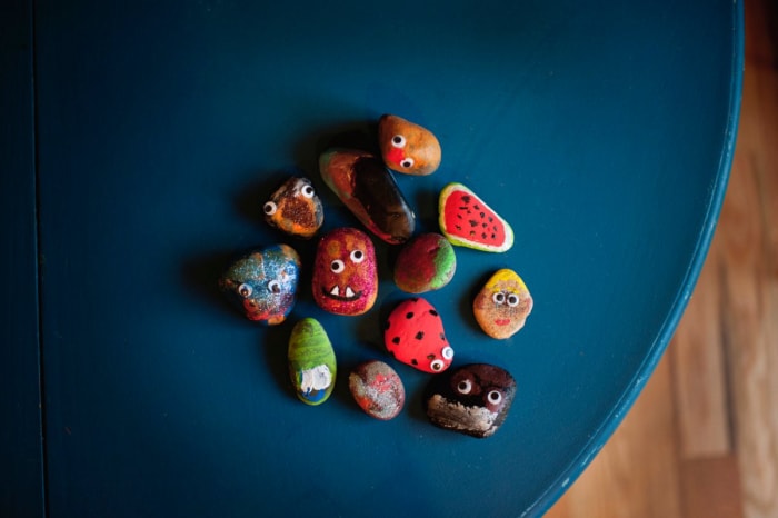 Des rochers peints aux yeux globuleux sont assis sur une table bleue.