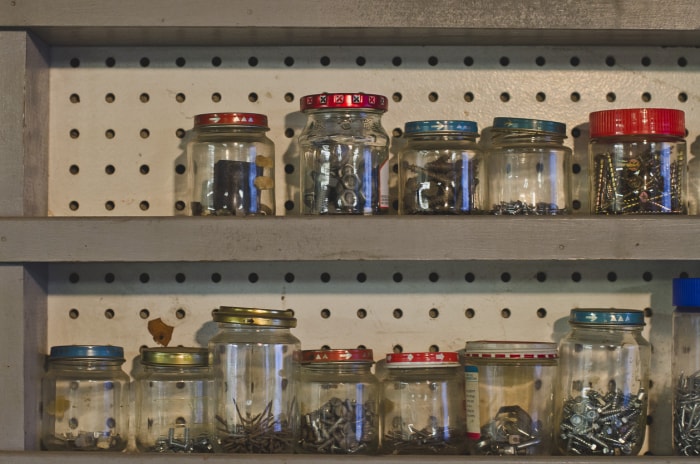 Une rangée d'étagères en bois dans un vieil atelier poussiéreux rempli de bocaux en verre et de vis dans l'ancien magasin gardant tout stocké.