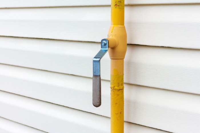 Conduite de gaz naturel de couleur jaune installée le long de l'extérieur d'une maison résidentielle.