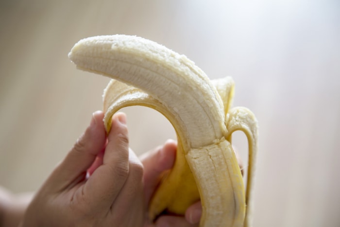 gros plan sur une main qui épluche une banane