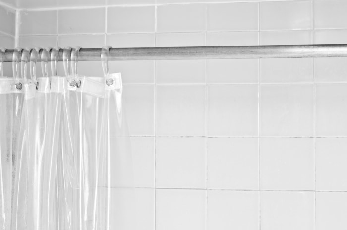 14 choses que vous ne saviez pas que vous pouviez nettoyer dans votre machine à laver doublure de rideau de douche transparente dans une salle de bain carrelée