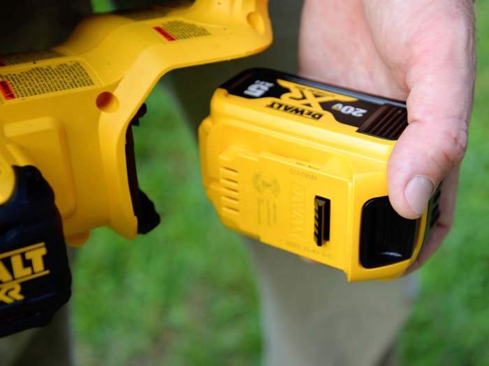 Quelqu'un installe une nouvelle batterie sur la tronçonneuse DeWalt 20V