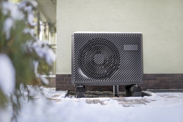 Une pompe à chaleur électrique à air installée à l’extérieur d’une maison en hiver.