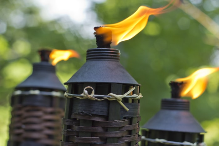 Trois torches à la citronnelle allumées avec des bases en bambou.