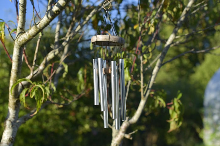 Des carillons de vent en argent sont suspendus à un arbre.