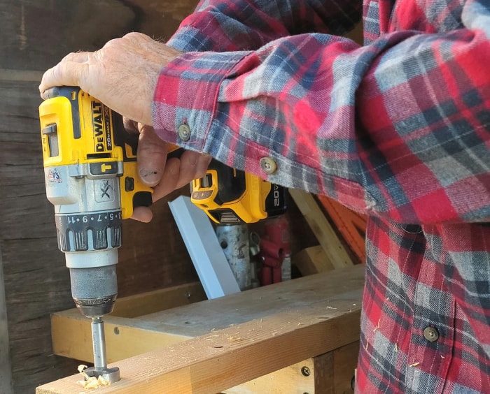 Une personne utilisant un outil DeWalt alimenté par une batterie DeWalt PowerStack pour percer un trou dans une pièce de bois.