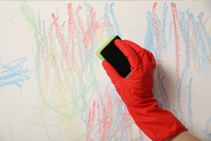 Une personne frotte des traces de crayon sur le mur avec une éponge.