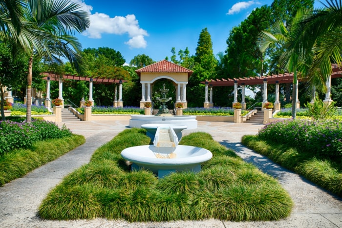 Vue de la fontaine dans un parc public avec un paysage herbeux et des arbres.