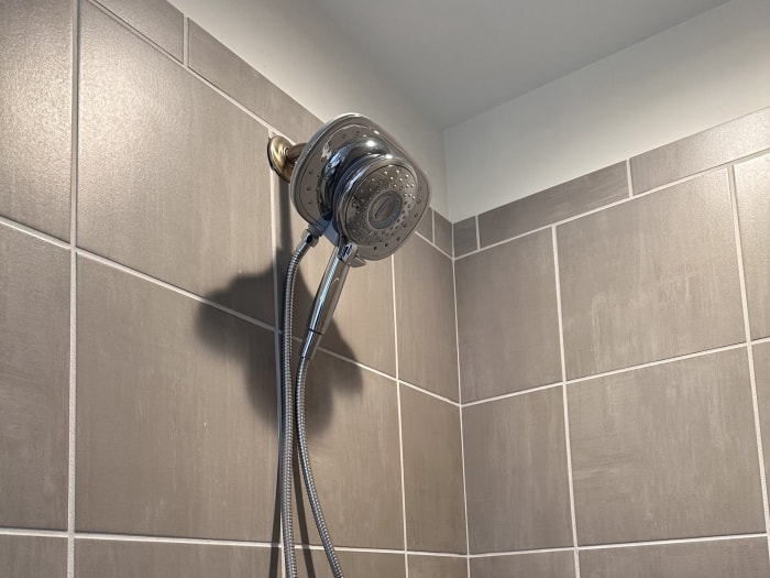 Pommeau de douche chromé American Standard Spectra Plus Duo monté sur un mur en carrelage taupe