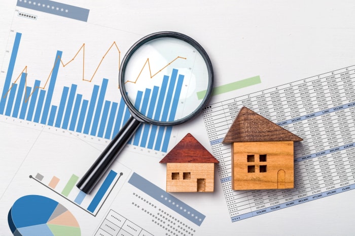 Loupe sur les graphiques d'investissement avec des mini maisons en bois