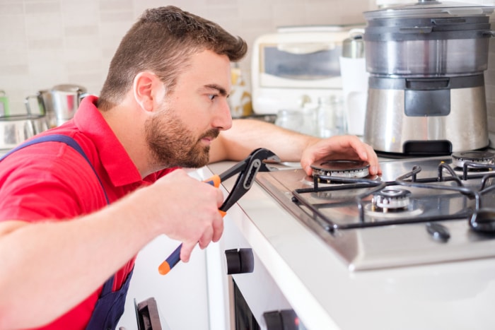 Bricoleur réparant la cuisinière à gaz dans la cuisine.