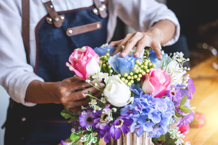 Personne arrangeant des fausses fleurs dans un vase.