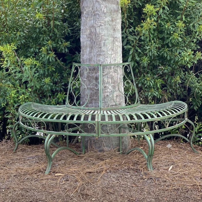 Banc de jardin en métal enveloppant un grand arbre.