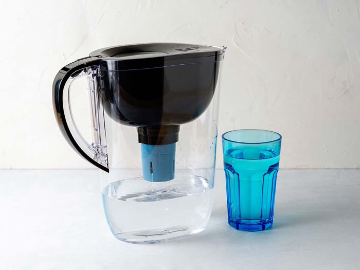 La carafe filtrante Brita Tahoe remplie d'eau à côté d'une tasse bleue