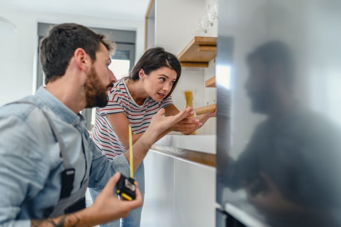 Un jeune couple répare un réfrigérateur. 