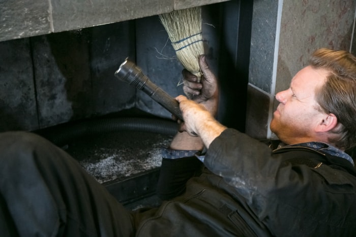 Ramoneur nettoyant la cheminée à l'intérieur de la maison