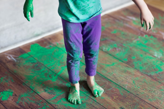 Un enfant et un plancher en bois recouverts de peinture verte.