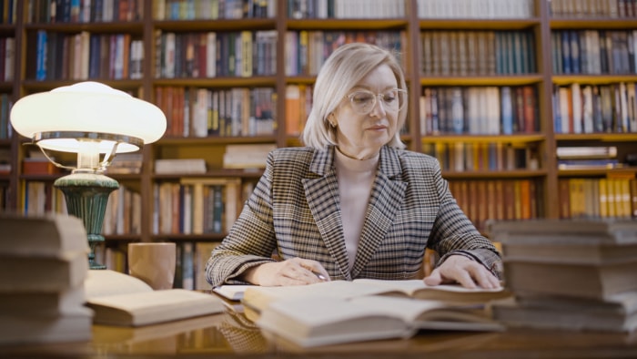 Bibliothécaire senior travaillant tard, lisant de nouveaux livres, occupation, recherche scientifique