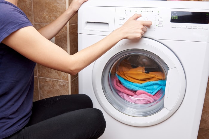 Femme utilisant un sèche-linge avec des vêtements à l'intérieur