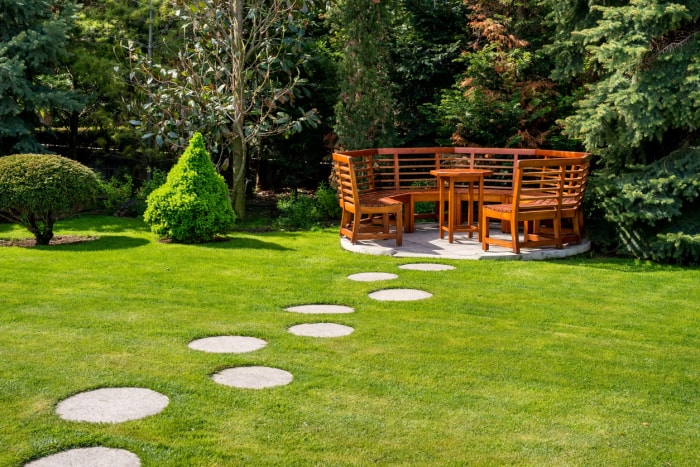 Grand banc de jardin en bois de forme circulaire avec dossiers hauts.