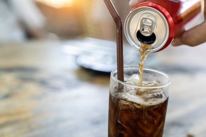 Verser du cola d'une canette dans un verre.